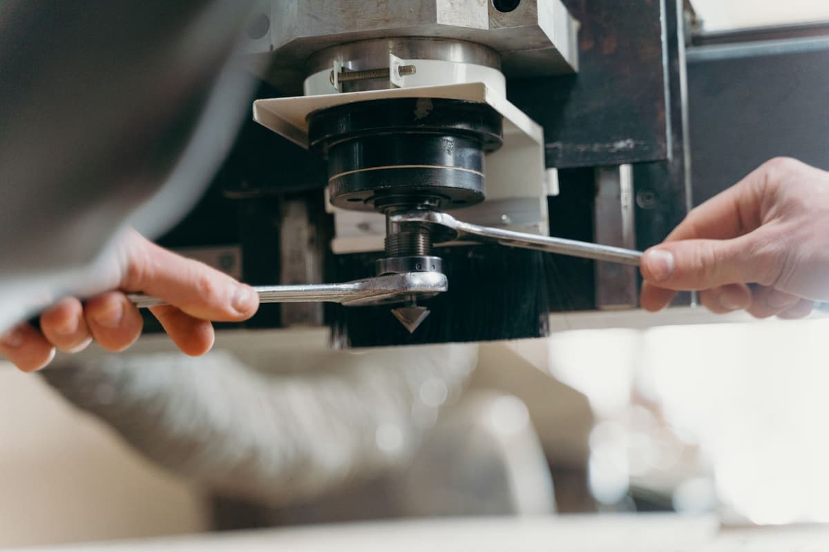 Tecnico che sostituisce l'utensile su un mandrino CNC con due chiavi